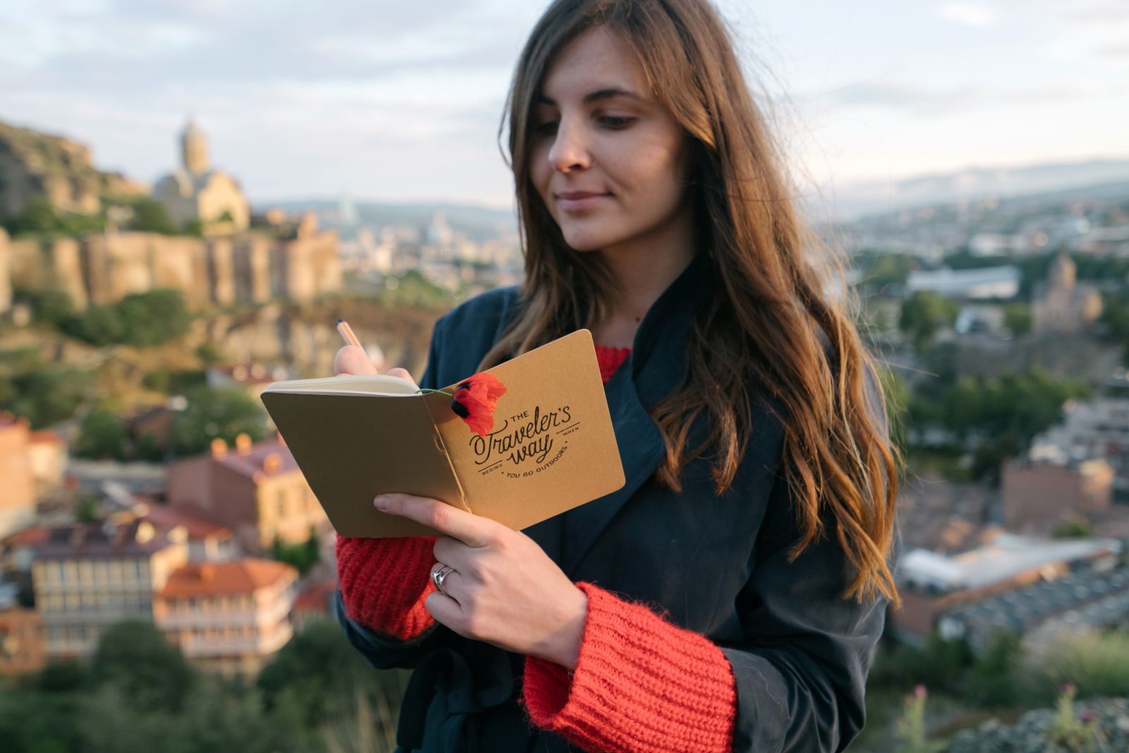 Traveler writing in a notebook above a hilltop old town