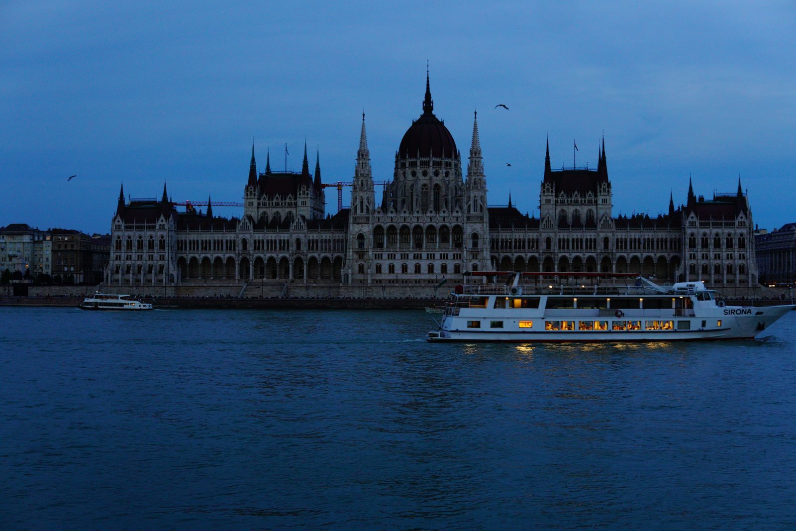 River boat passing the Hungarian Parliament on the Danube at dusk - river cruise reviews and survey findings
