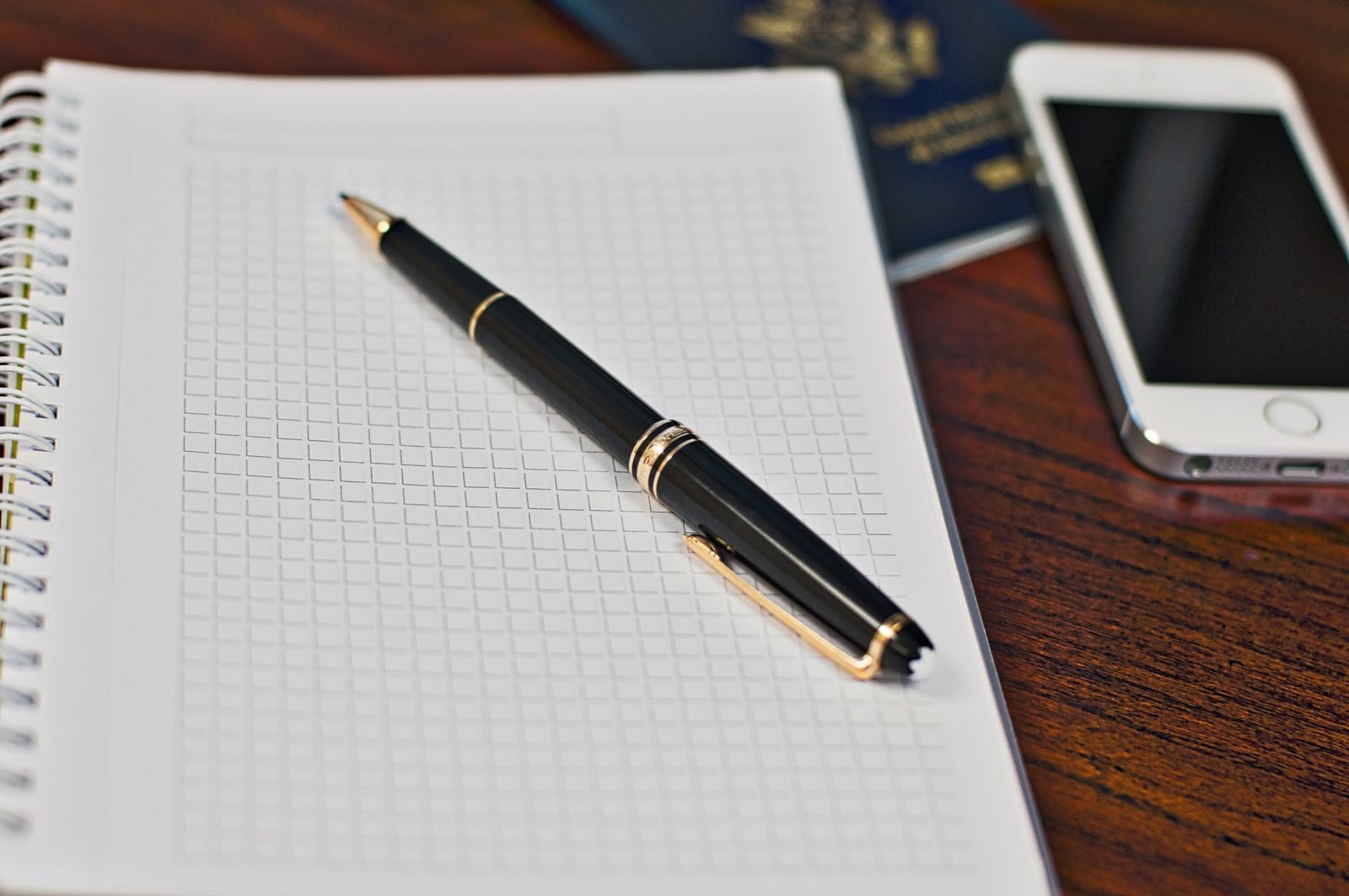 Notebook, pen, phone and passport on a desk, ready to plan a trip